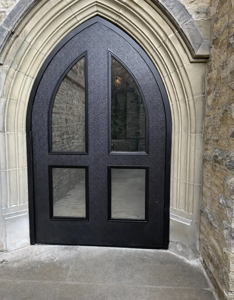 Porte Special-Lite noire sur mesure à arc gothique avec vitrages, encastrée dans une ouverture en pierre